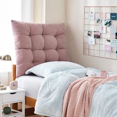 a bed with pink and blue comforters in a bedroom next to a white table