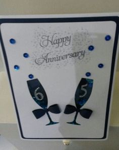 an anniversary card with two wine glasses on the front, and blue confetti around the edges