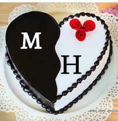 a heart - shaped cake with the letter m on it and two roses in the middle