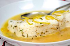 a white bowl filled with fish covered in lemon sauce