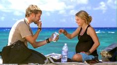 a man sitting next to a woman on top of a beach