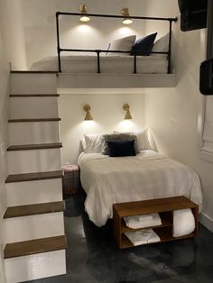 a bed sitting under a loft next to a stair case in a room with white walls