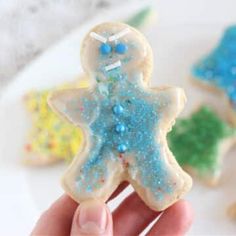 a hand is holding some cookies with blue and green icing