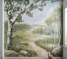 a cat sitting on the floor in front of a wall mural with a forest scene