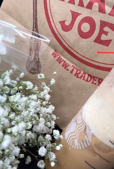 there is a vase with flowers in it next to a bag that says starbucks joe