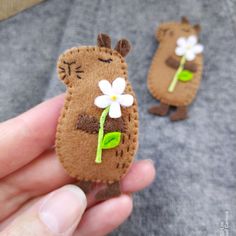 someone is holding two small felt animals with flowers on them