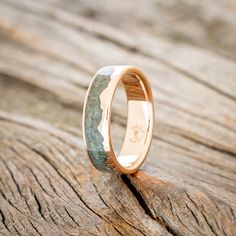 a wooden surface with a wedding ring on it's side, sitting on top of a piece of wood