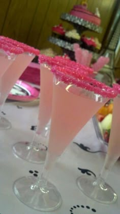 three martini glasses filled with pink liquid on top of a white tablecloth covered table