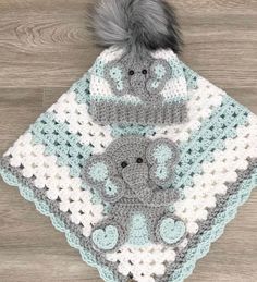 a crocheted elephant blanket and hat on top of a wooden floor