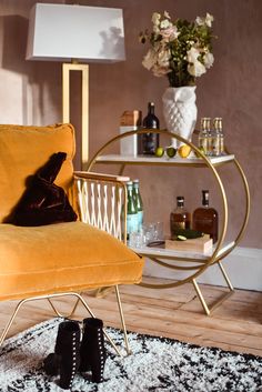 a yellow chair sitting on top of a wooden floor next to a table filled with bottles