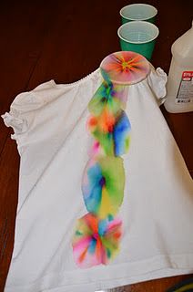 a tie - dyed t - shirt is sitting on a table next to plastic cups