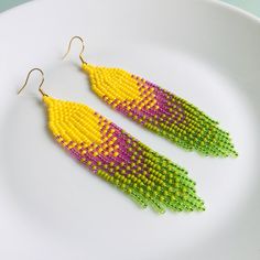 Add bright colors to your summer everyday outfit with this pair of beaded fringe earrings. Inspired by tribal style, these waterfall earrings are made from high-quality Czech seed beads and supplied with stainless steel accessories. This pair is made with a colorful gradient pattern consisting of yellow, pink, and light green colors. It is created for those who love wearing bold artisan earrings in bohemian or hippie style. These statement seed bead earrings become a highlight of your look. Measurements:  Length: 4.13'' / 10,5 cm Width: 0.79'' / 2 cm Material: Czech seed beads, stainless steel accessories. 100% top quality handmade earrings The real color of the item may be slightly different from the picture shown on website caused by the brightness of your monitor. If you have special si Summer Beaded Earrings With Fringe And Round Beads, Summer Beaded Earrings With Round Beads And Fringe, Summer Beaded Fringe Earrings With Round Beads, Summer Festival Chandelier Earrings With Round Beads, Multicolor Chandelier Earrings For Summer Beach, Multicolor Chandelier Earrings For Beach And Summer, Multicolor Summer Chandelier Earrings For Beach, Summer Multicolor Chandelier Earrings For Beach, Summer Beach Tassel Earrings With Beaded Fringe