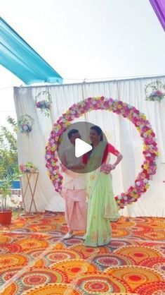 a man and woman are standing in front of a decorated circle with flowers on it