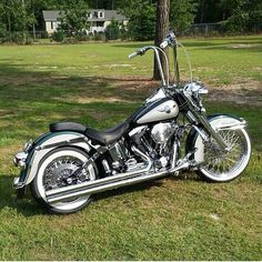 a white and black motorcycle parked on top of a grass covered field next to a tree