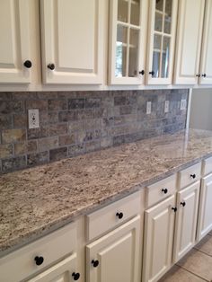 a kitchen with white cabinets and granite counter tops