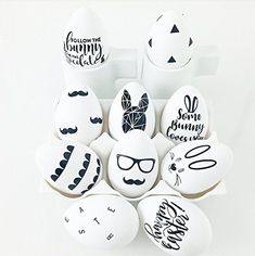 an arrangement of decorated eggs with black and white designs on them, including mustaches