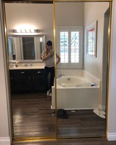 a woman is taking a selfie in the mirror while standing next to a bathtub