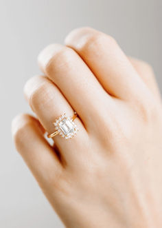 a woman's hand holding an engagement ring with a diamond in the middle and side