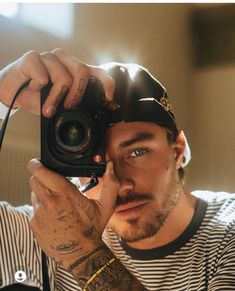 a man holding up a camera to take a selfie with his hat over his head