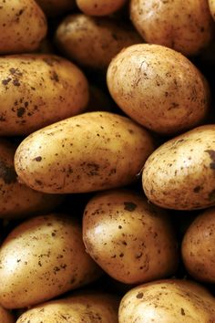 potatoes with dirt on them are piled up