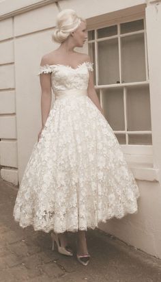 a woman standing in front of a window wearing a white dress