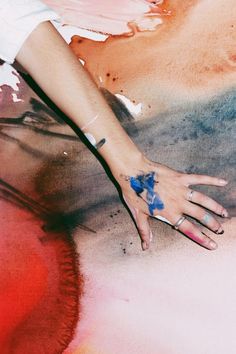 a woman's hand with blue and white designs on her left wrist, holding onto the ground