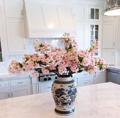 a vase filled with pink flowers sitting on top of a kitchen counter next to an oven