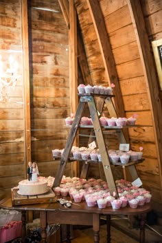 a wooden table topped with lots of cakes and cupcakes