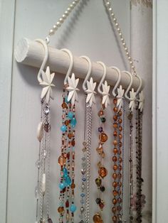 a bunch of necklaces hanging from a hook on a door handle with beads and pearls attached to it