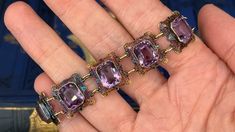 This fantastic vintage bracelet features nine (9) rectangular filigree links each accented with one (1) cut-cornered rectangular modified brilliant cut amethyst set into bezel settings. The links feature a pierced design with engraved details and bordered with milgrain edging. The bracelet measures 6-1/4 inches in length and 15.7mm in width. The bracelet is finished with a spring ring style clasp. The patina on this bracelet is spectacular. Antique Purple Bracelets For Formal Occasions, Formal Victorian Jewelry With Rectangular Shape, Rectangular Victorian Jewelry For Formal Occasions, Formal Victorian Rectangular Jewelry, Ornate Rectangular Jewelry For Collectors, Ornate Rectangular Collectible Jewelry, Purple Amethyst Art Deco Jewelry, Antique Jewelry With Gemstone Accents For Formal Occasions, Luxury Rectangular Jewelry With Intricate Design