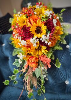 a bridal bouquet with sunflowers and other flowers on a blue velvet couch