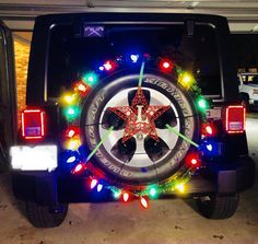 a jeep decorated with christmas lights and a star on the front wheel tire cover is parked in a garage