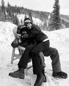 two people sitting on a bench in the snow