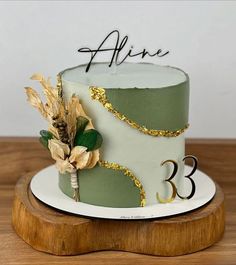 a green and white cake with gold decorations on it's side sitting on a wooden stand