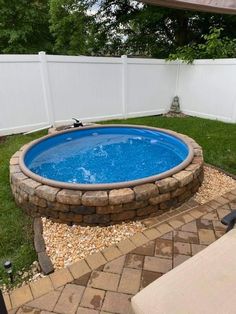 an above ground swimming pool surrounded by gravel and stones in a backyard with a white privacy fence