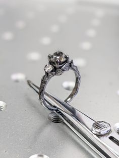 a diamond ring sitting on top of a pair of scissors with drops of water around it