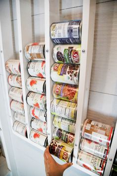 a person is reaching for canned food in a refrigerator