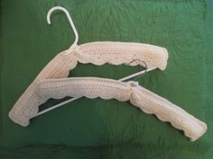 two white crocheted clothes hangers on a green quilt