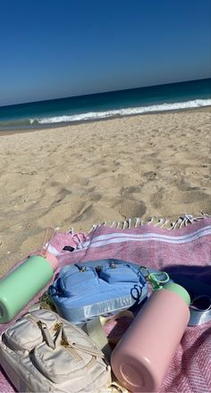 a beach towel and some water bottles on the sand