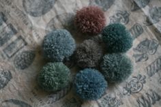 four different colored pom poms sitting on top of a piece of paper next to each other