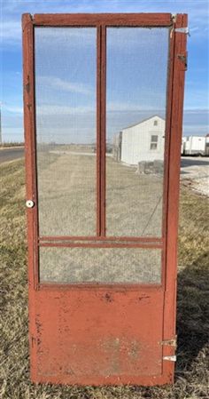 an old red door sitting in the middle of a field