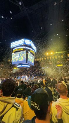 the crowd is throwing confetti in the air at a basketball game on a big screen