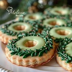 green frosted donuts with sprinkles and holly decorations on a white plate