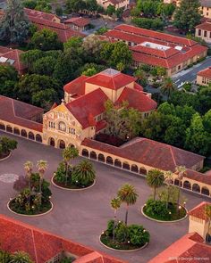 an aerial view of a large building surrounded by trees and buildings in the distance are many palm trees