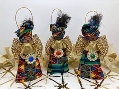 three african dolls are standing next to each other on a white surface with gold sequins