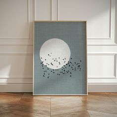 an art print with birds flying in the sky above it on a wood floor next to a wall