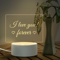 i love you forever illuminated sign next to a vase with flowers in it on a table