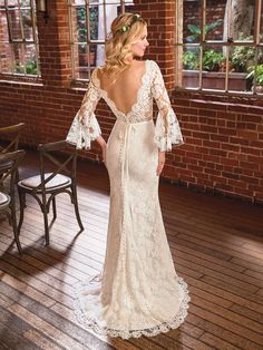 a woman in a wedding dress standing on a wooden floor next to a brick wall