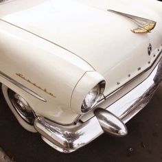 an old white car is parked on the street