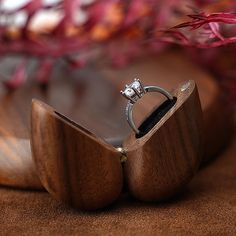 a wooden box with a wedding ring in it sitting on top of a brown surface